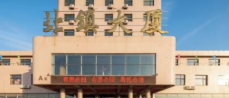 Un edificio con un gran letrero que dice 'Beijing Hotel' y una placa con caracteres chinos.