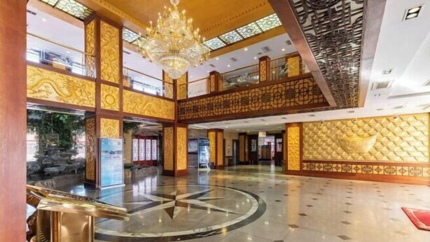 A spacious lobby with a grand chandelier, a central circular design on the floor, and ornate wall panels. - Beizhen Hotel (Beizhen)