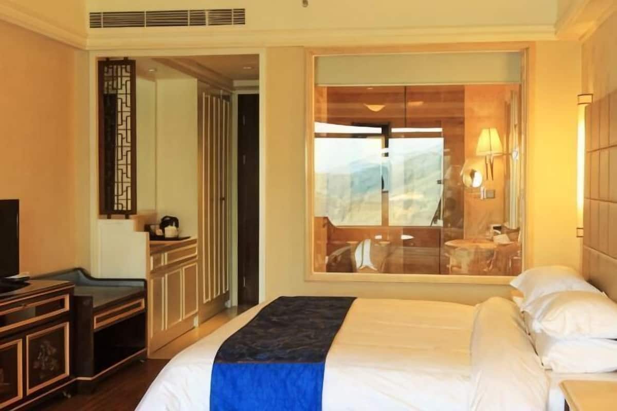 Ein Hotelzimmer mit Bett, Fernseher, Schreibtisch und Fenster mit Aussicht.