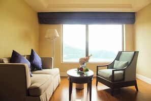 Een woonkamer met een bank, fauteuil en een ronde tafel met een bloevas.