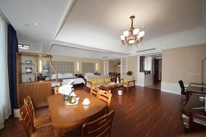 Een ruime hotelkamer met een zithoek, een groot bed, een bank en een kroonluchter.