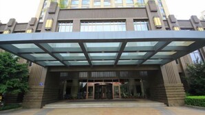 A modern hotel entrance with a glass canopy, a central revolving door, and a circular driveway. - Shansong Hotel Shunchang (Shunchang)