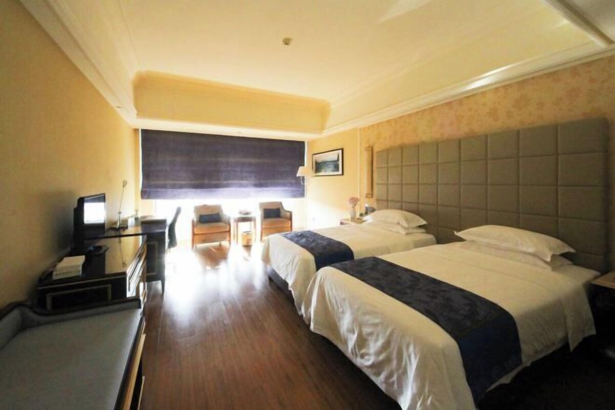 Een hotelkamer met twee bedden, een bureau met een computer, een stoel en een kleine tafel.