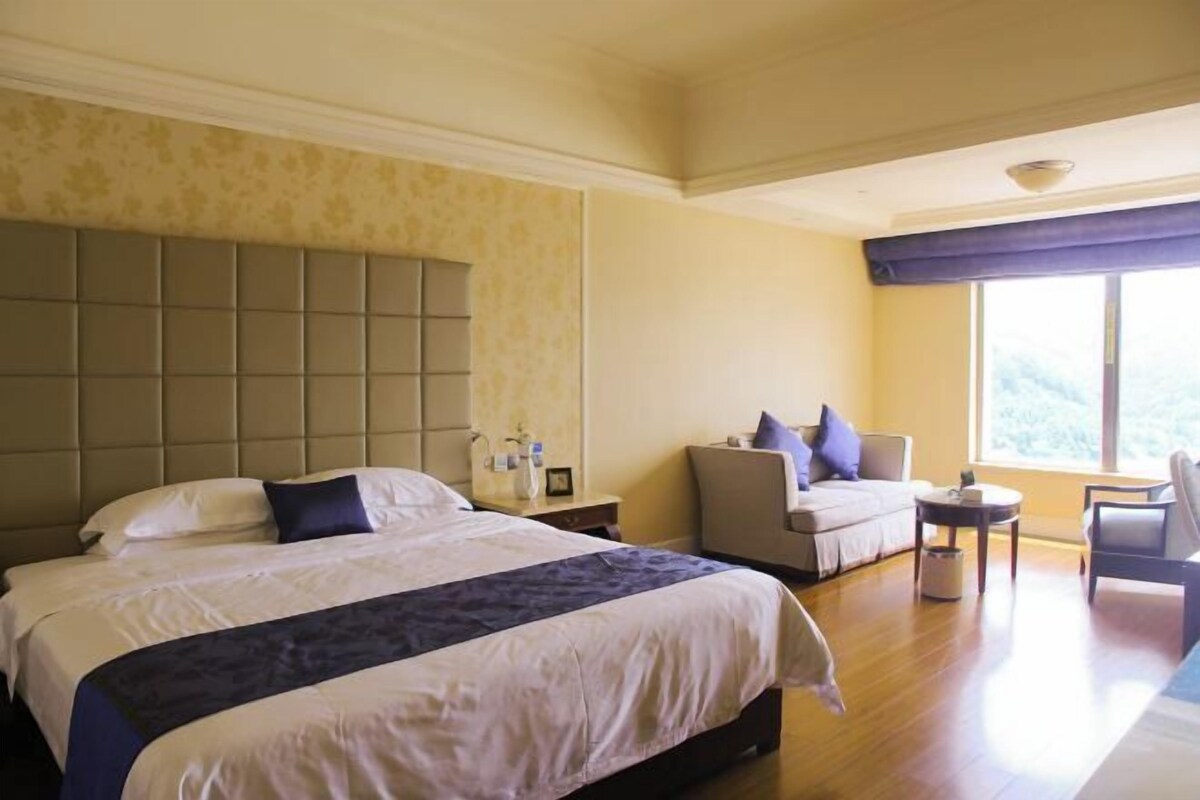 Een hotelkamer met een groot bed, een bank, een tafeltje en een raam met uitzicht.