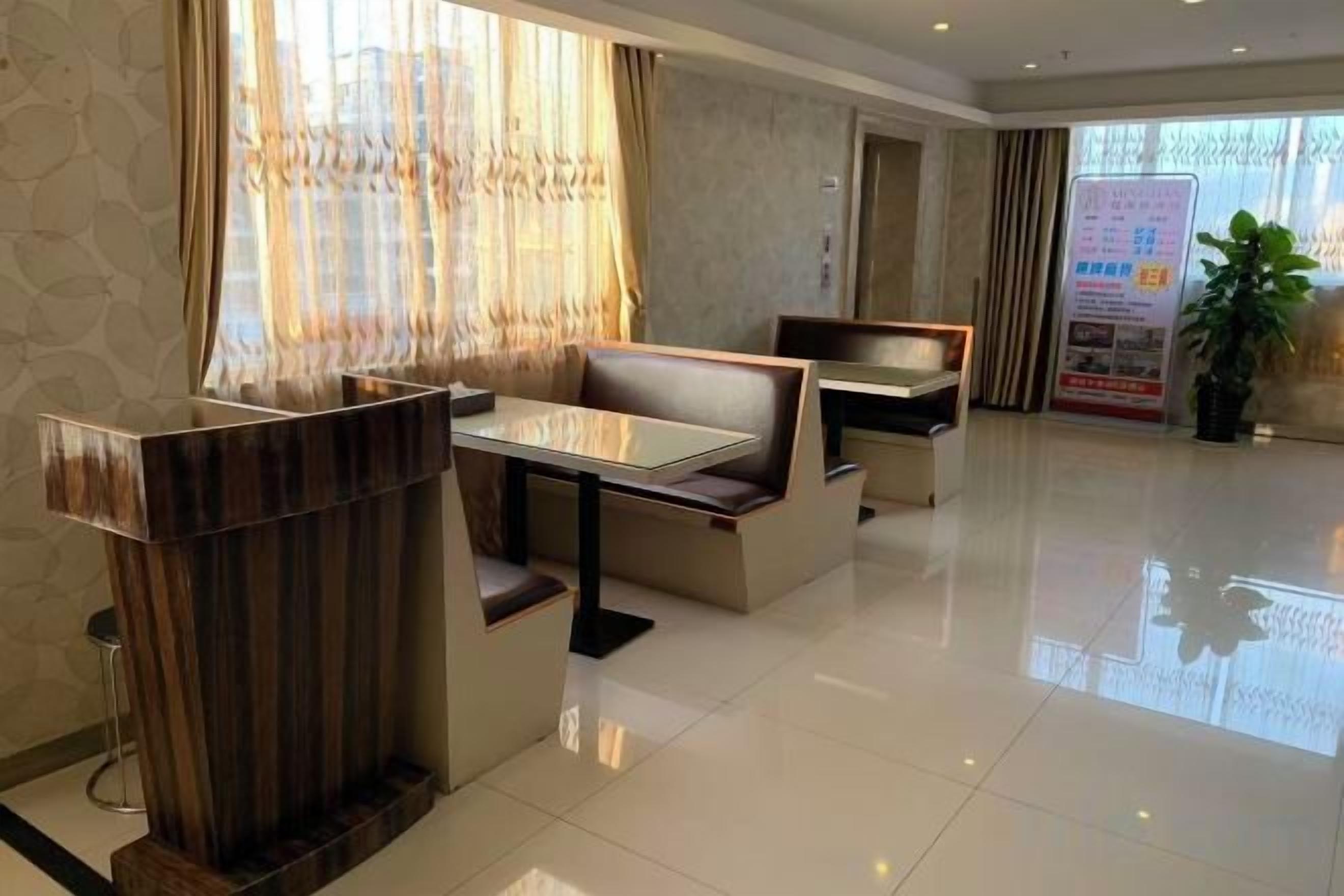 A hotel lobby with a reception desk, seating area, and a large window with curtains.