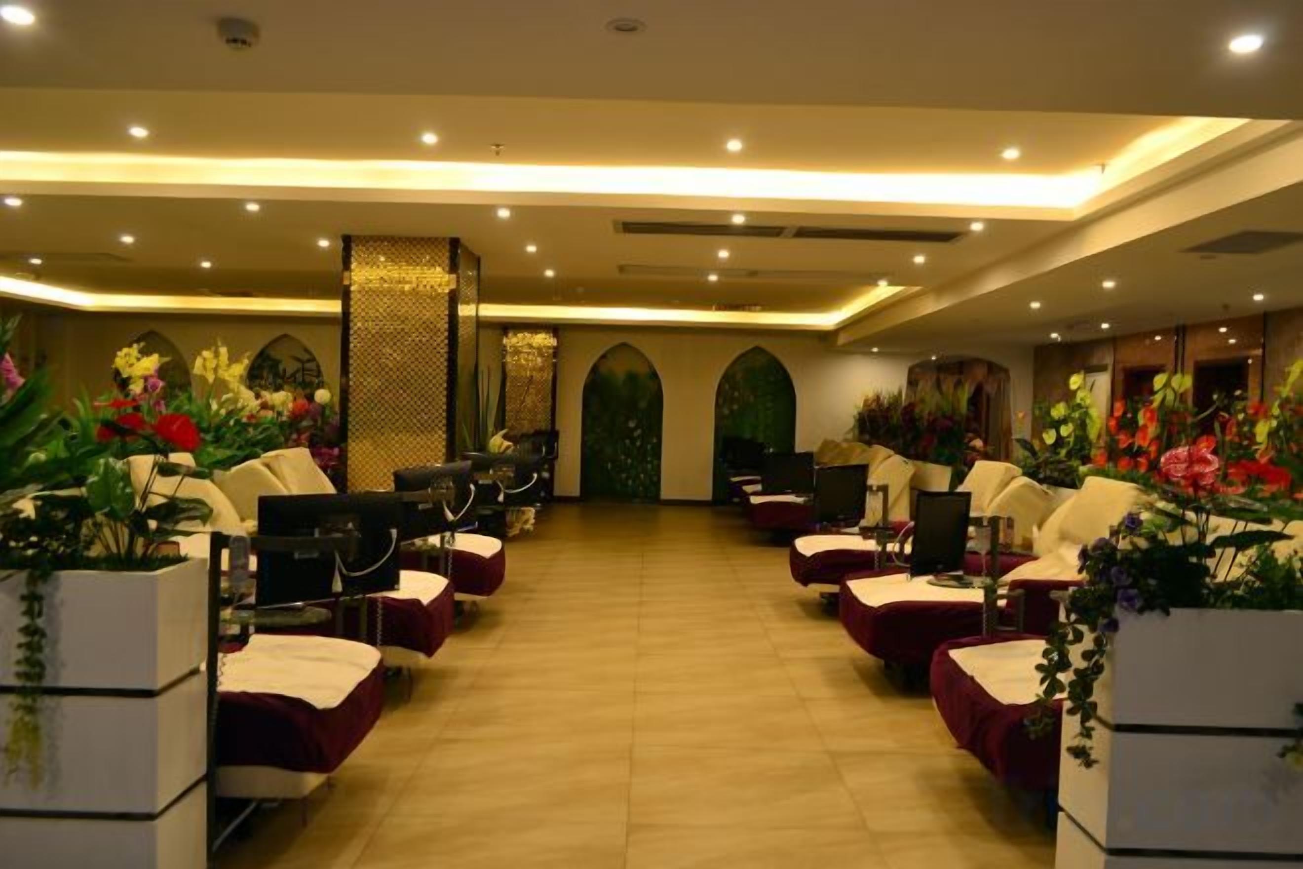 A hotel room with a long corridor, seating area with chairs, and potted plants.