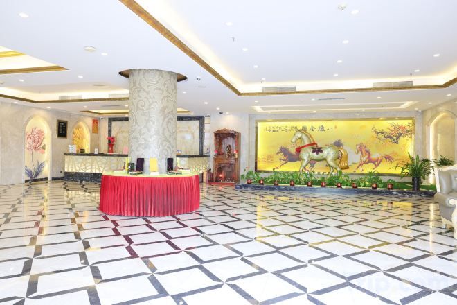 A hotel lobby with a reception desk, a large pillar, and a mural with horses.