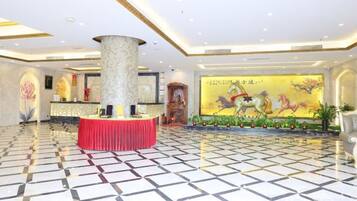 A hotel lobby with a reception desk, a large pillar, and a mural with horses.