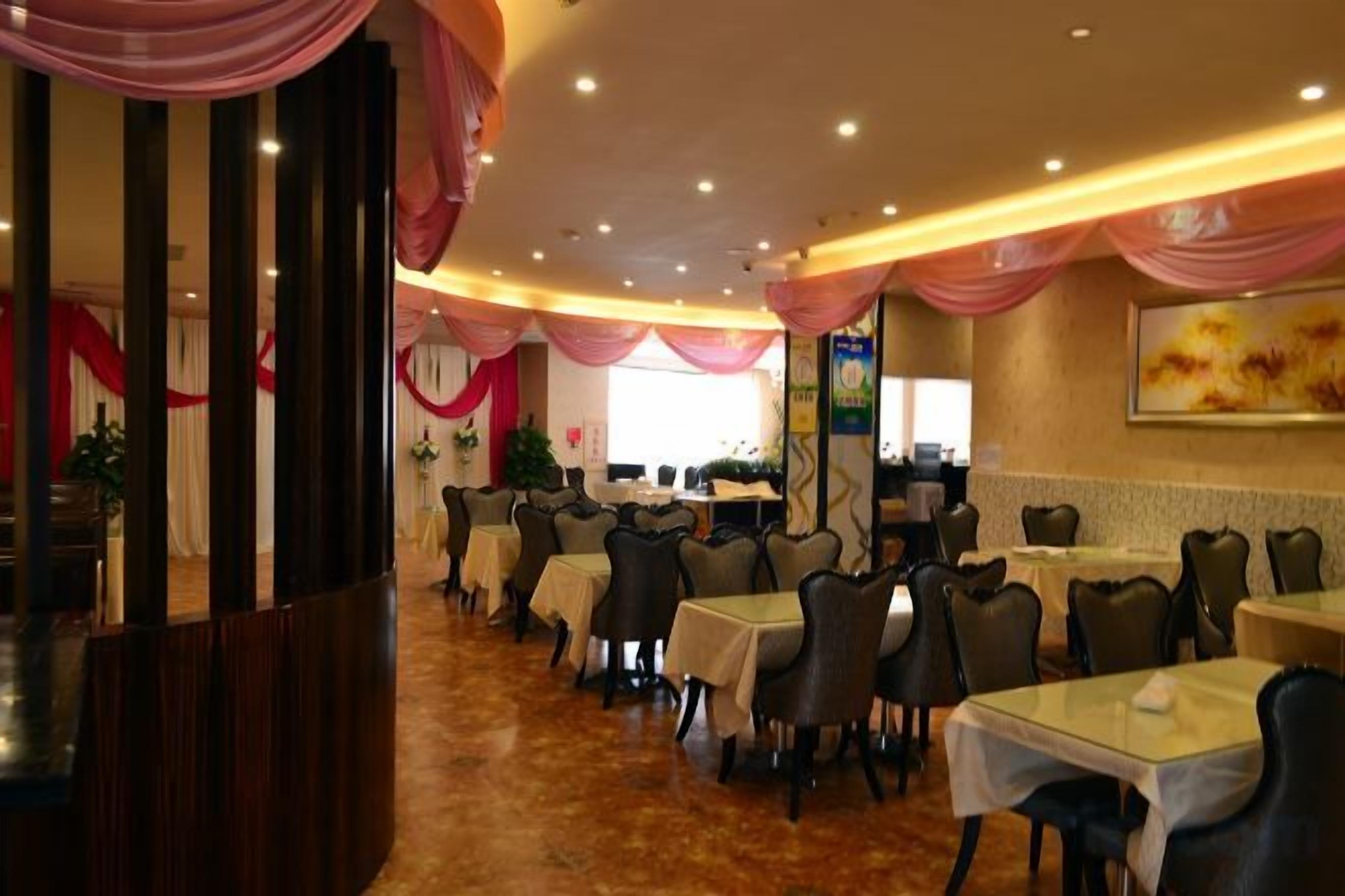 A restaurant with multiple tables and chairs, a counter area, and a decorative ceiling.