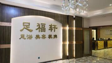 A reception area with a reception desk, a chandelier, and a sign with Chinese characters.