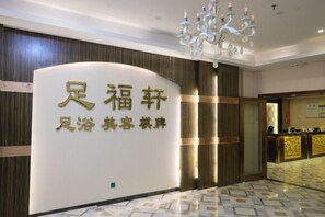 A reception area with a reception desk, a chandelier, and a sign with Chinese characters.