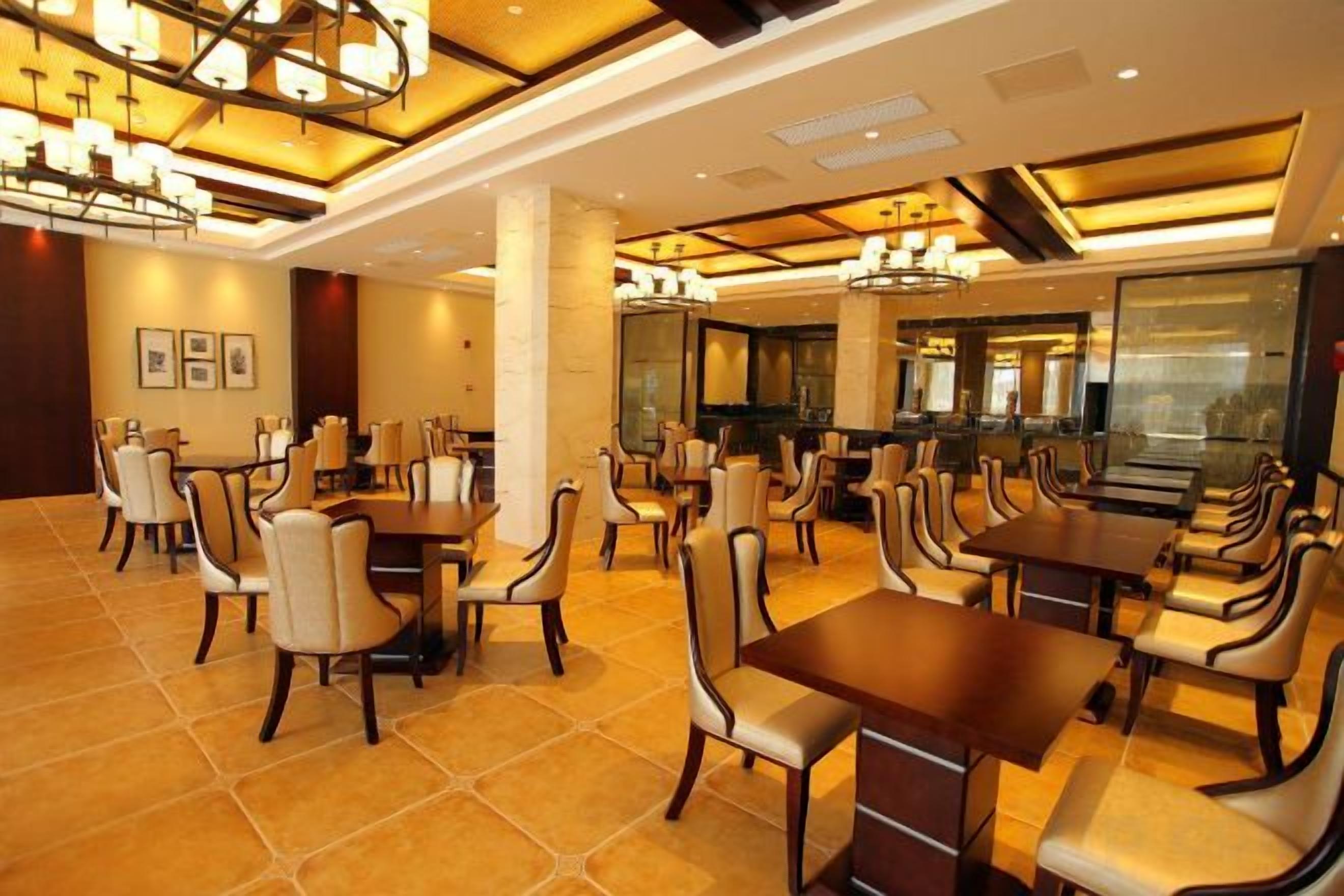 Un restaurant doté de nombreuses tables et chaises, d’un lustre et d’un décor intérieur moderne.