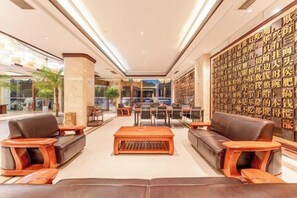 A hotel lobby with seating areas, a reception desk, and a wall with text. - Chuanyu Holiday Hotel (Dongtai)