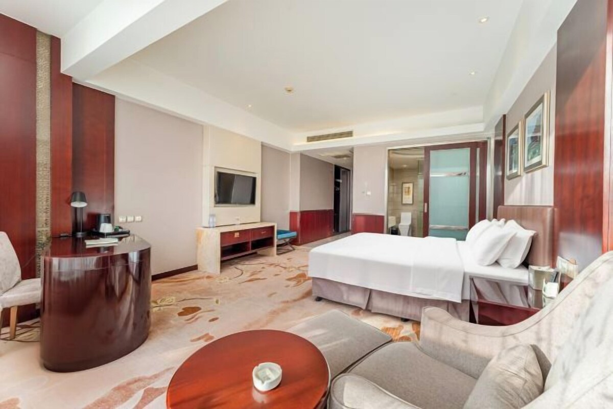 Een hotelkamer met een bed, een bureau, een televisie en een zithoek.