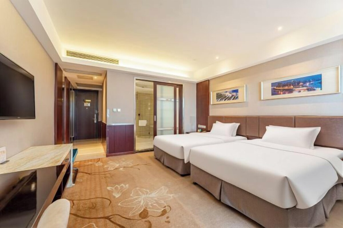 Een hotelkamer met twee bedden, een bureau, een flatscreen-tv en een deur naar een badkamer.