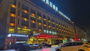 A hotel with multiple floors, illuminated windows, and a prominent sign. - Chuanyu Holiday Hotel (Dongtai)