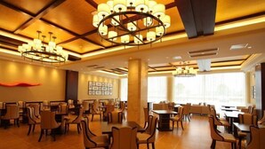 A spacious dining area with multiple tables and chairs, large chandeliers, and a modern ceiling design. - Chuanyu Holiday Hotel (Dongtai)