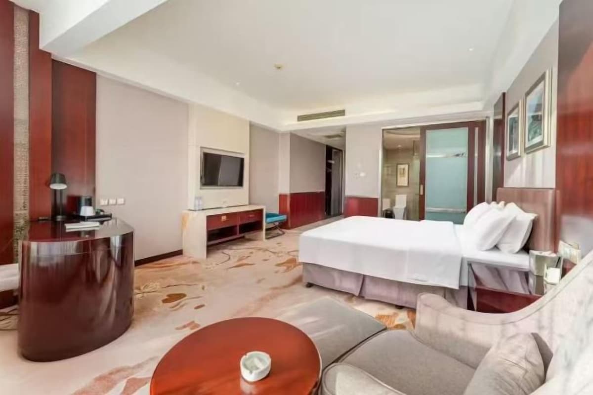 Une chambre d’hôtel avec un lit, un bureau, une télévision et un canapé.