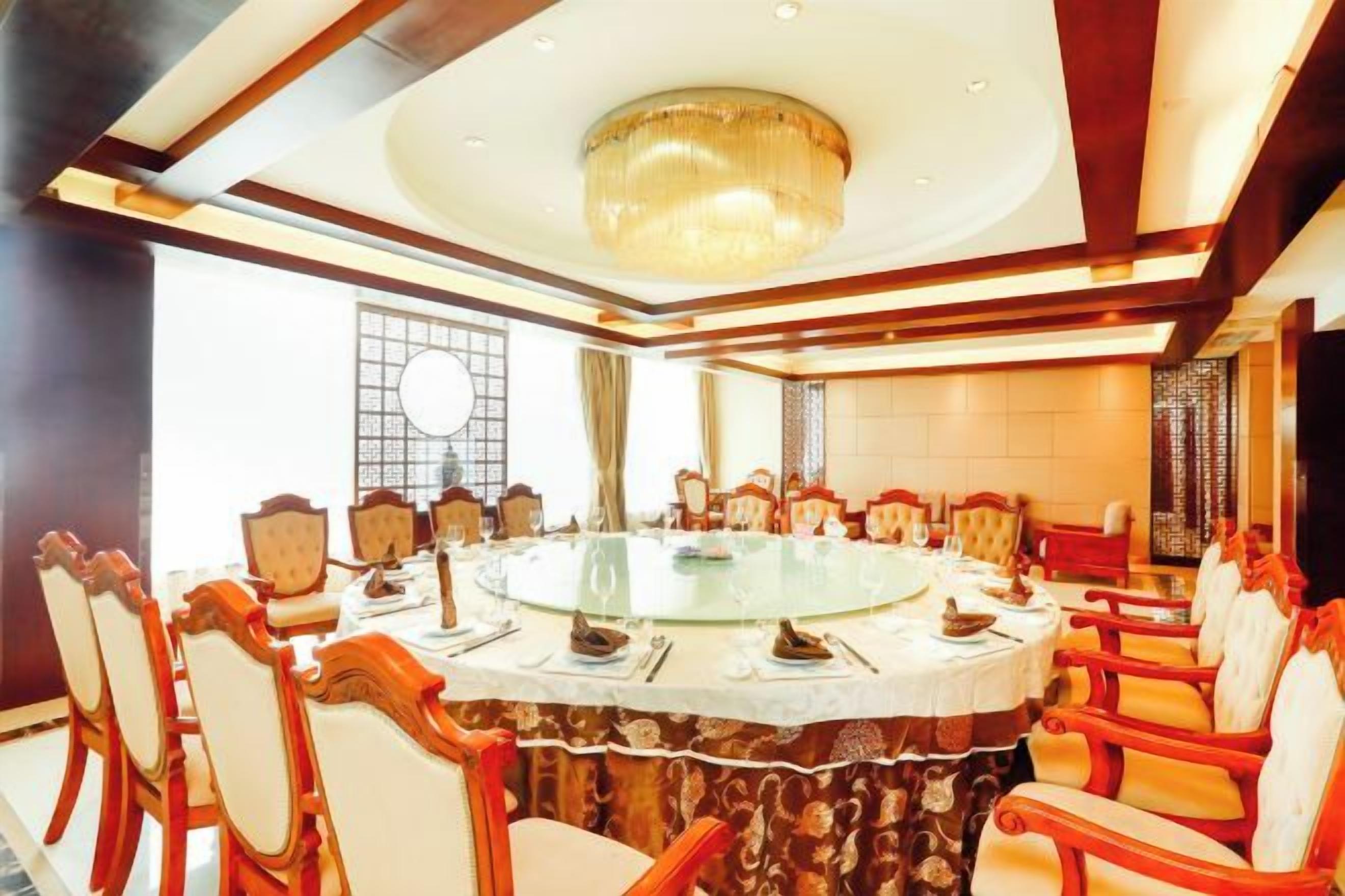 A conference room with a round table, chairs, and a chandelier.