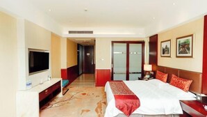 A hotel room with a bed, a TV, a desk, and a door leading to a hallway. - Chuanyu Holiday Hotel (Dongtai)