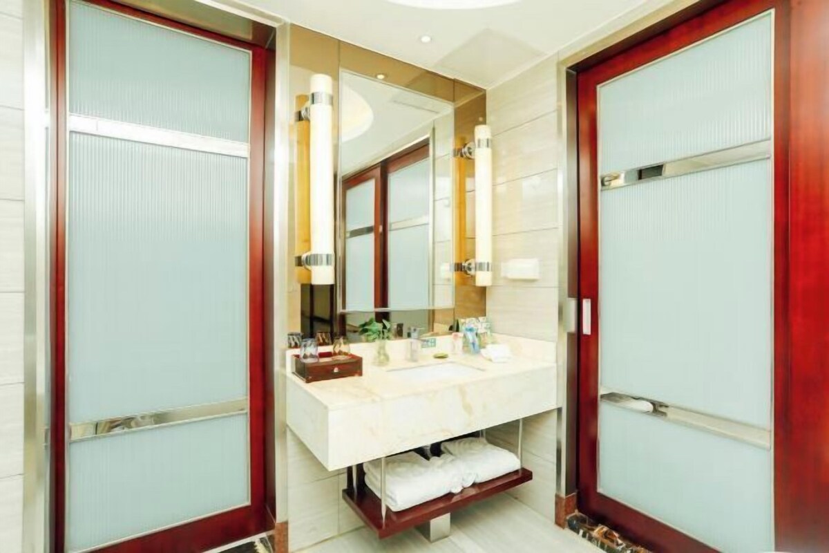 A modern bathroom with a large mirror, a vanity with a sink, and a towel rack.
