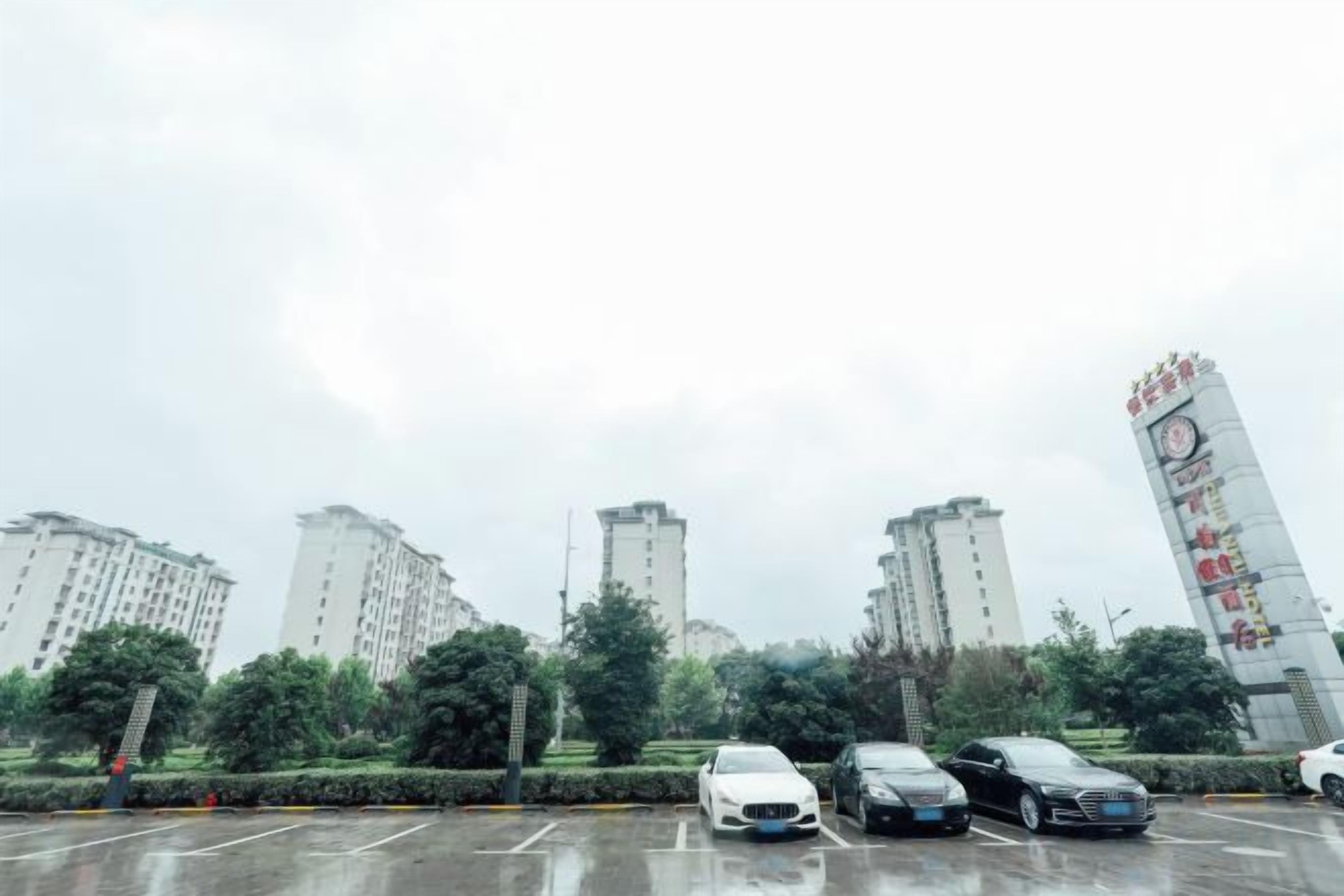 A parking lot with multiple cars and tall residential buildings in the background.