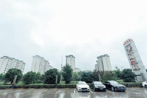 Een parkeerplaats met meerdere auto's en hoge woongebouwen op de achtergrond.