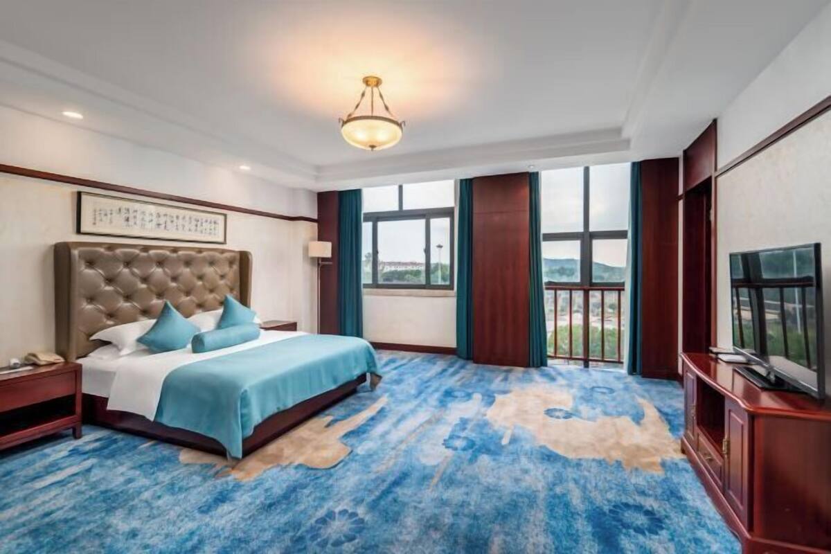 A hotel room with a large bed, a television, and a view of the outdoors.