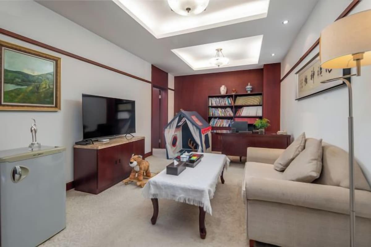 Una sala de estar con televisor, estantería y sofá.