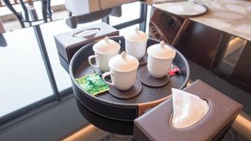 A tray with four white cups and a tissue box on a glass table.