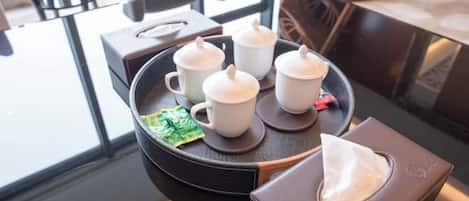 A tray with four white cups and a tissue box on a glass table.