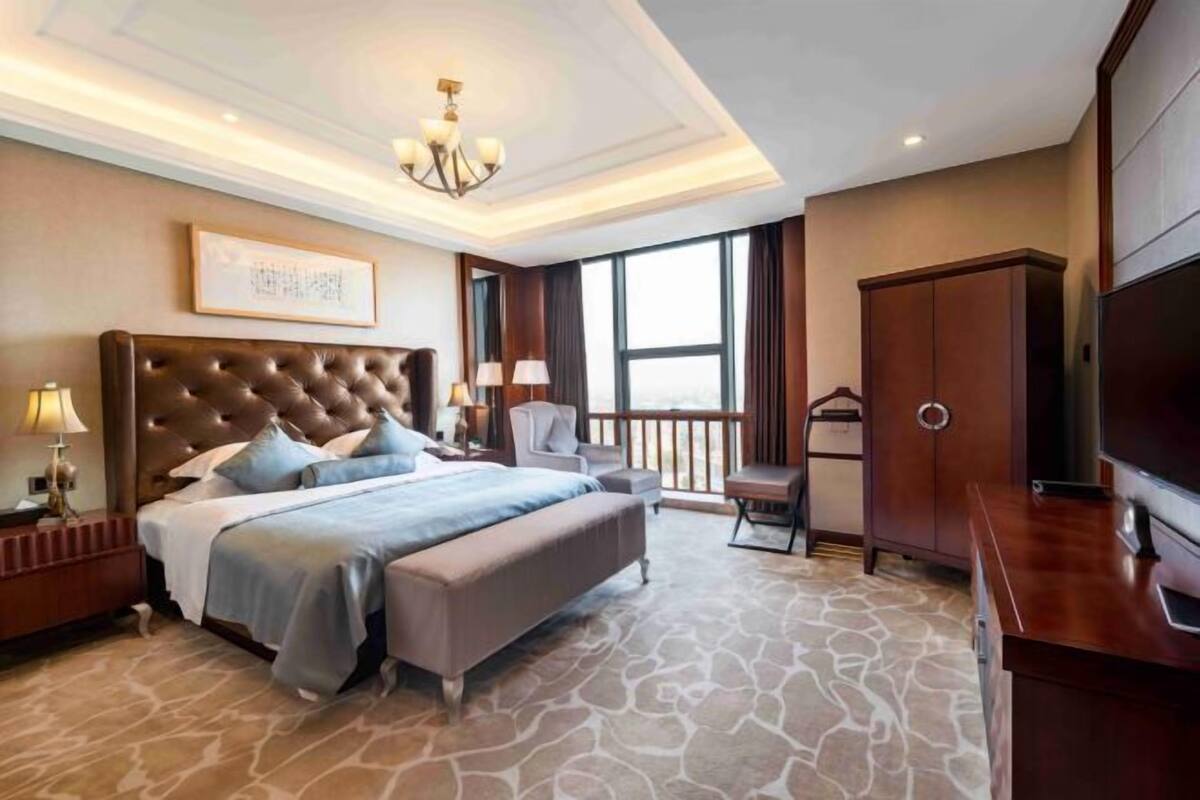 A spacious bedroom with a large bed, a TV, and a wardrobe.