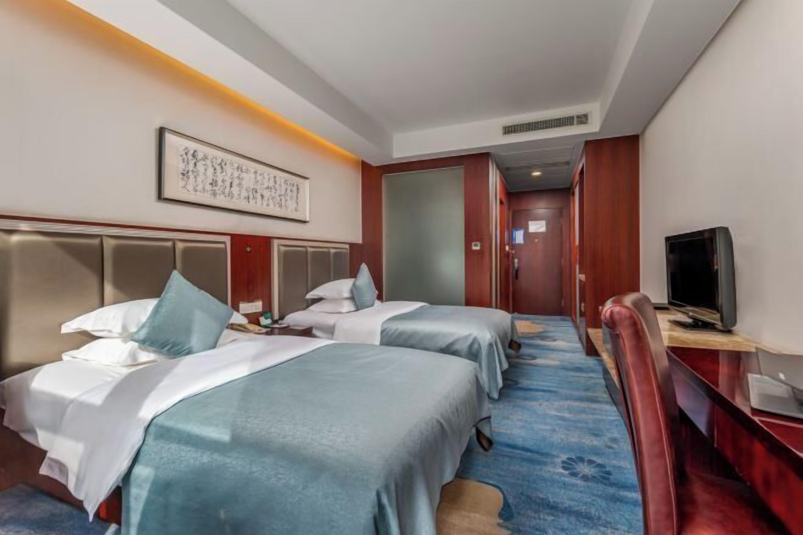 Habitación de hotel con dos camas, televisión y un pasillo que lleva a otra habitación.