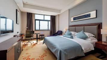 Ein Hotelzimmer mit Bett, Schreibtisch, Stuhl und einem großen Fenster.