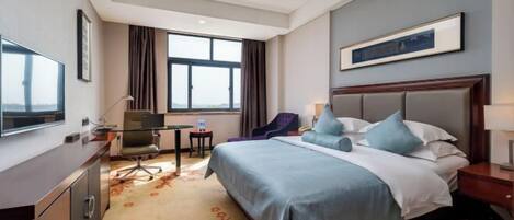 Una habitación de hotel con cama, escritorio, silla y un ventanal grande.