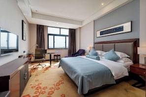 Ein Hotelzimmer mit Bett, Schreibtisch, Stuhl und einem großen Fenster.