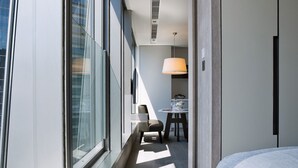 A modern hotel room with a large window, a bed, a desk, and a chair. - One96 (Hong Kong)
