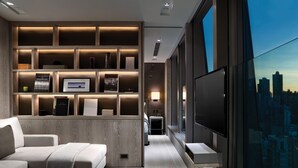 A modern living room with a large TV, a sofa, and a built-in shelving unit with books and decorative items. - One96 (Hong Kong)