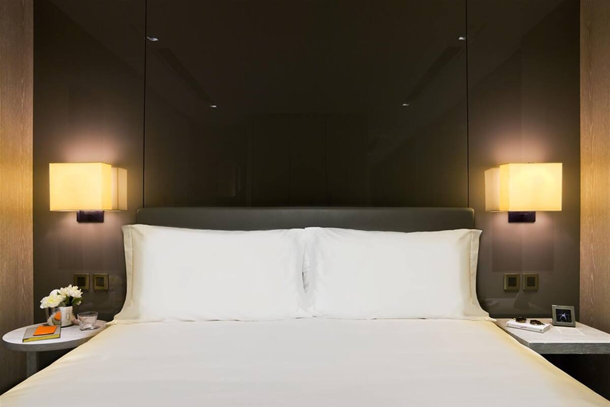 A hotel room with a large bed, two bedside tables, and wall-mounted lamps.