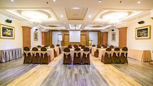 A conference room with multiple tables and chairs, a podium, and framed artwork on the walls. - Adina Hotel (Da Nang)