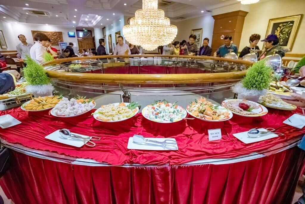 Ein reichhaltiges Buffet mit verschiedenen Speisen und Besteck auf einer roten Tischdecke.