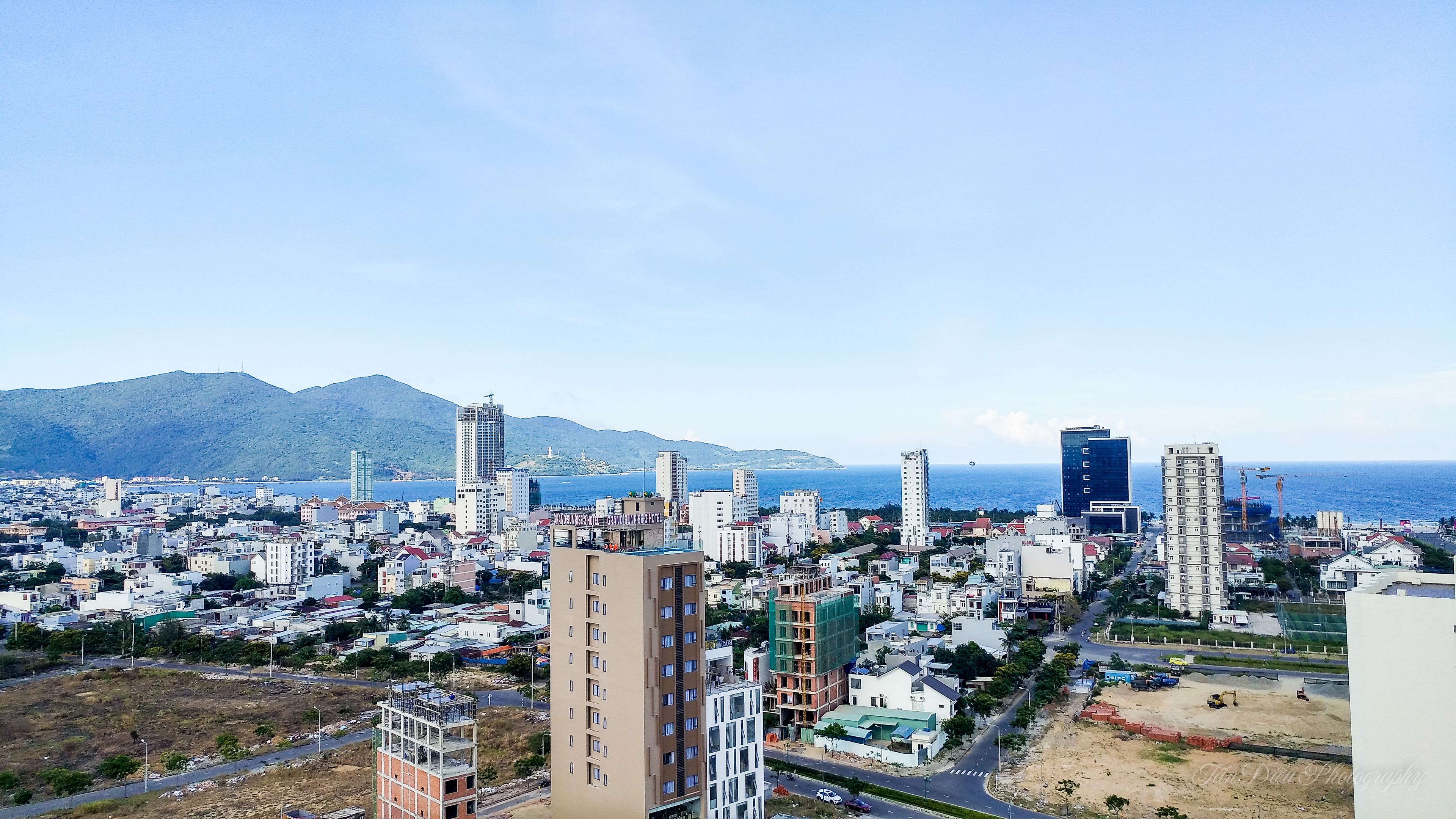 Un paisaje urbano con vista al mar y montañas al fondo.
