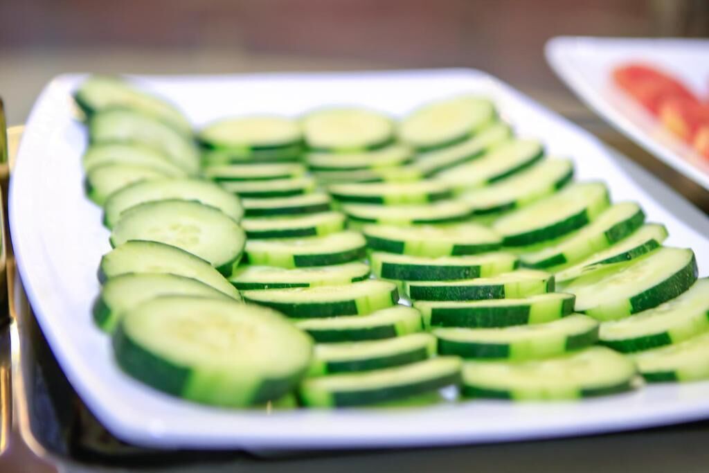 A white rectangular plate with neatly arranged cucumber slices.