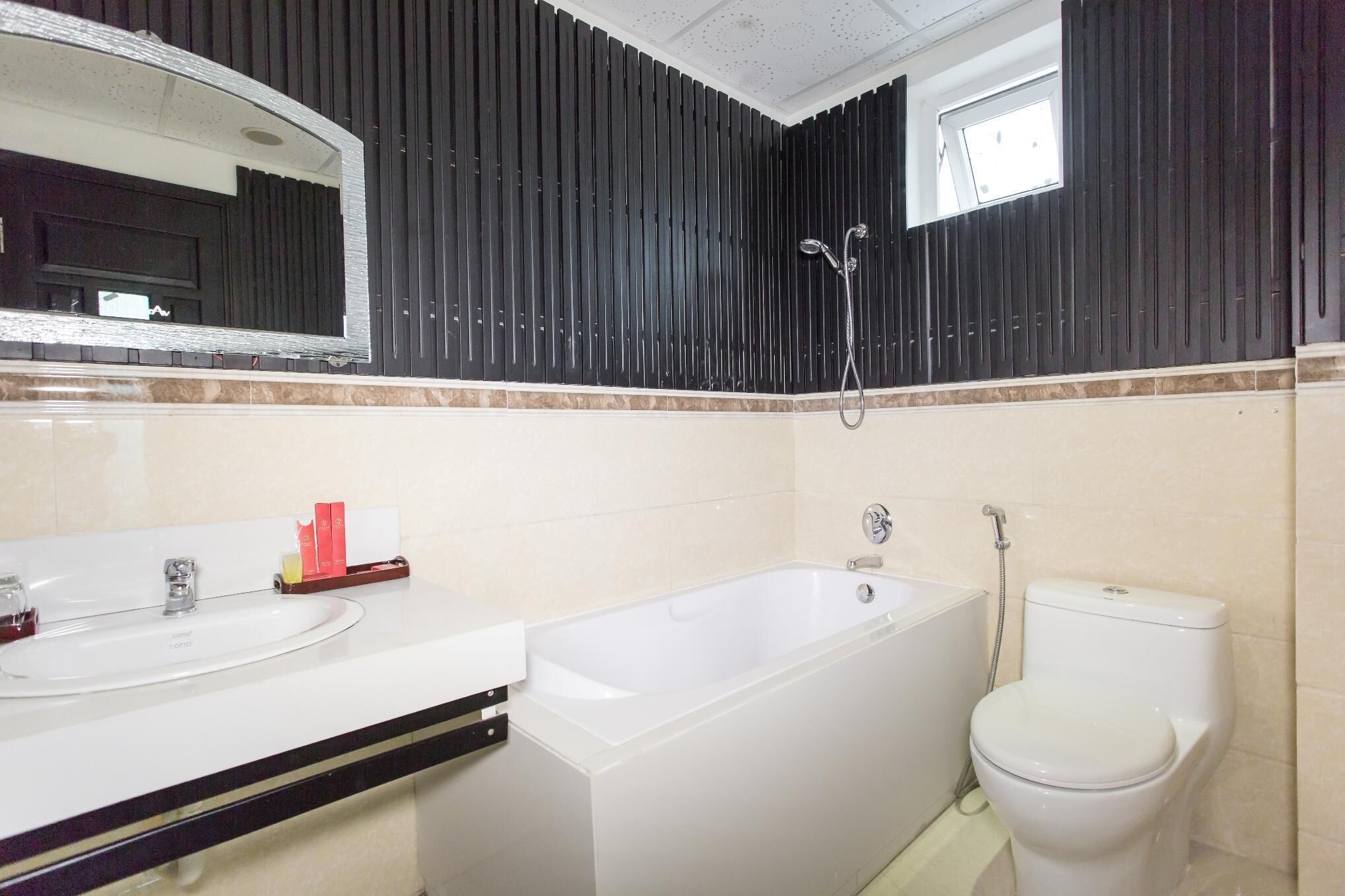 Un baño con una bañera blanca, un inodoro y un lavabo con un espejo encima.