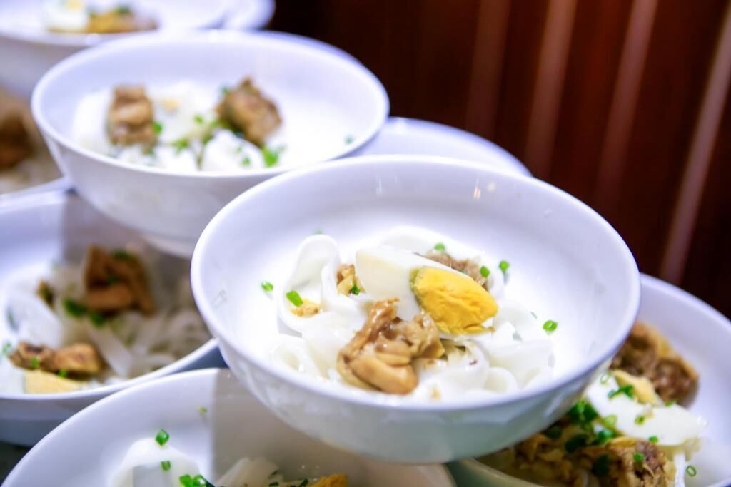A bowl of noodle soup with egg and meat garnished with green onions.