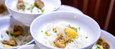 A bowl of noodle soup with egg and meat garnished with green onions.