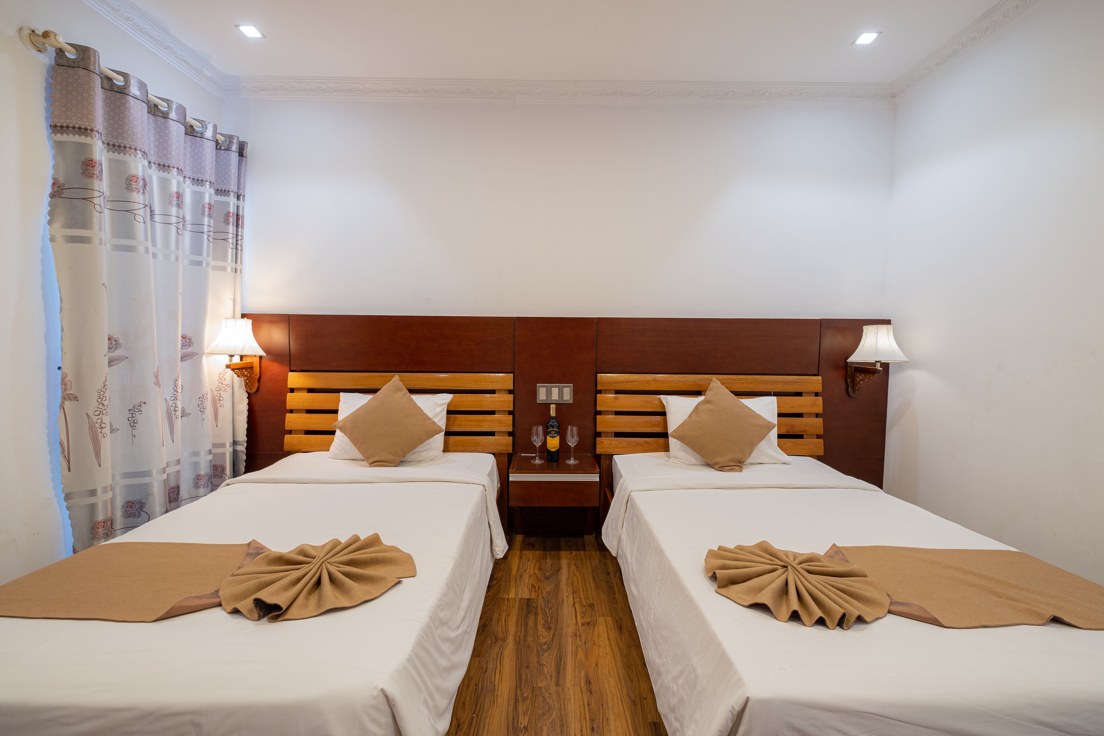 Une chambre d’hôtel avec deux lits, des têtes de lit en bois et une table de chevet avec une lampe.