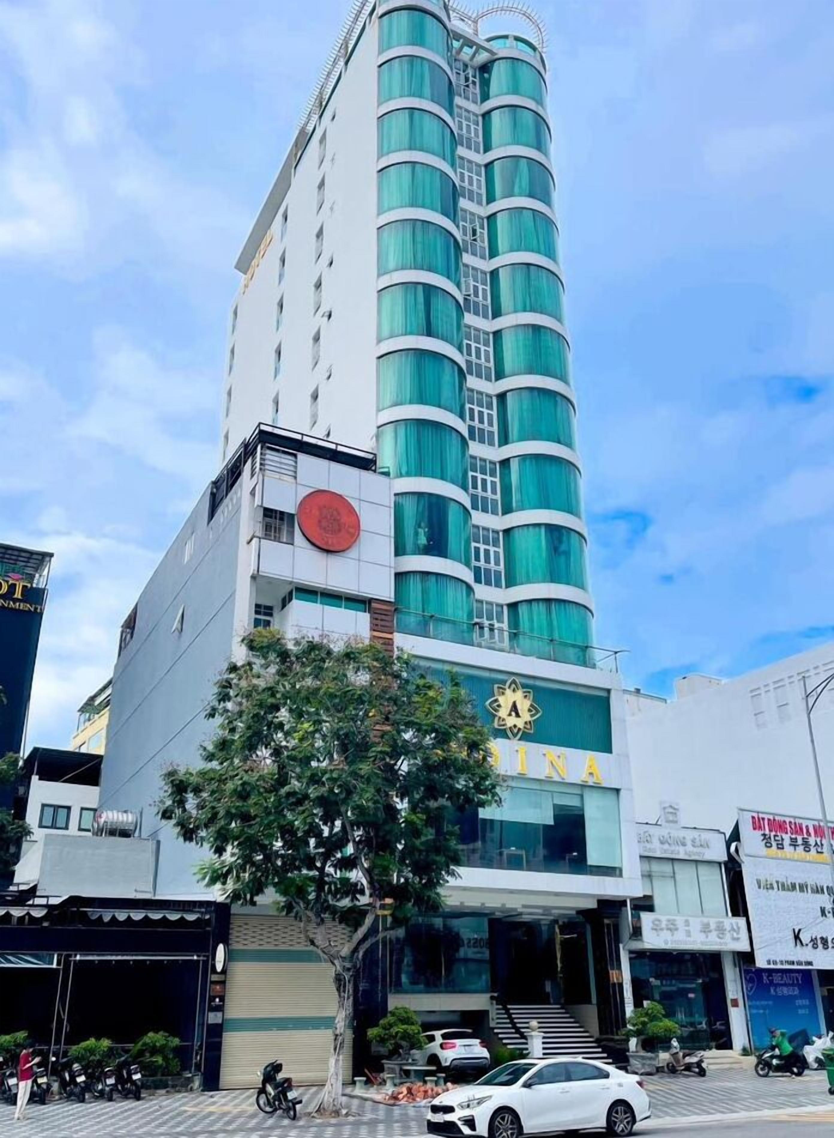 A multi-story hotel with a prominent 'INN' sign, a staircase leading to the entrance, and a tree in front.