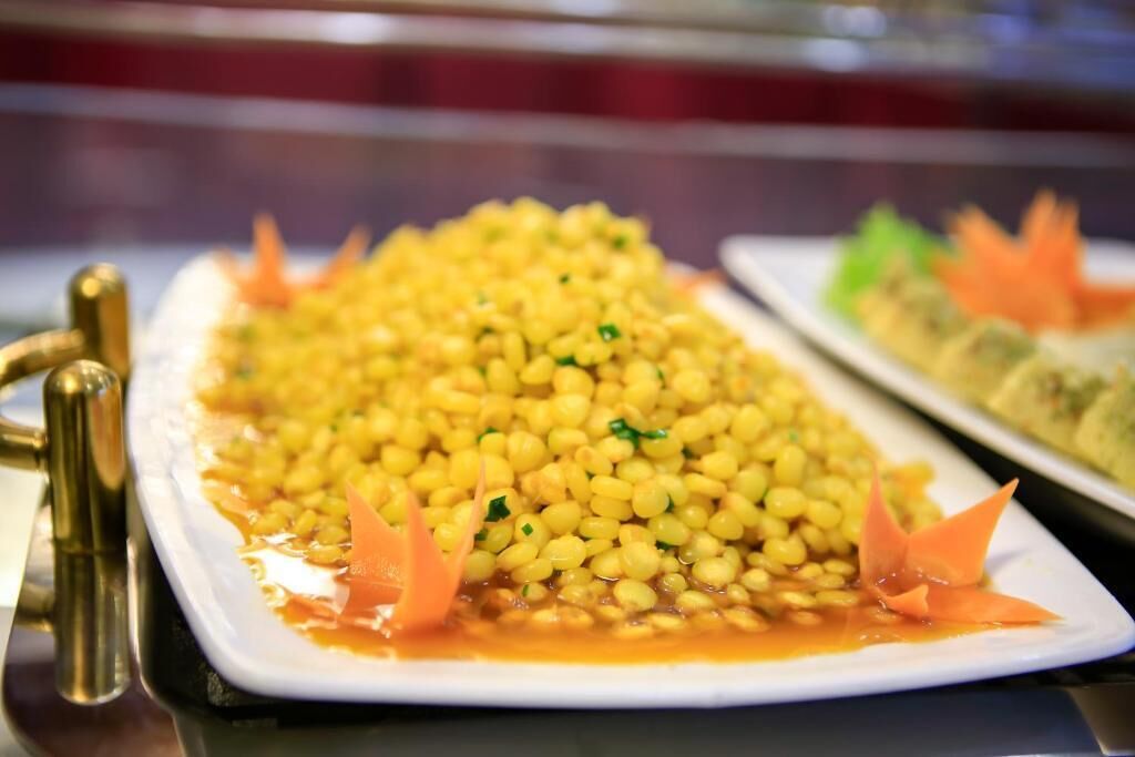 A buffet table with a large serving of yellow lentils garnished with carrot slices.