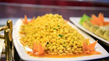 A buffet table with a large serving of yellow lentils garnished with carrot slices.